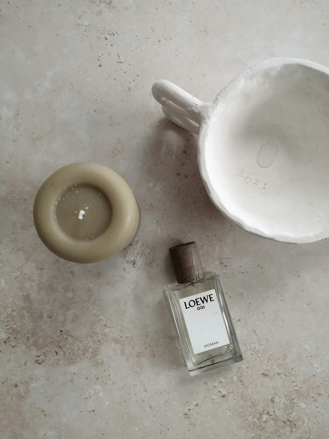 Candle, ceramics and fragrance on warm stone